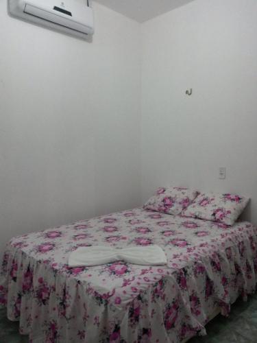 a bedroom with a bed with a flowered blanket at Suíte central Pousada in Jijoca de Jericoacoara