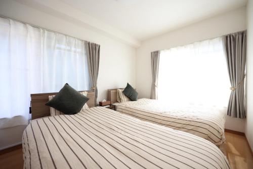 two beds in a room with a window at New コスパ重視セール開催中!久留米駅徒歩5分コンビニ1分!ファミリー 友人快適!キッズエリア大好評 in Kurume
