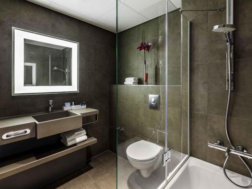 ein Badezimmer mit Dusche, Toilette und Waschbecken in der Unterkunft Novotel The Hague World Forum in Den Haag