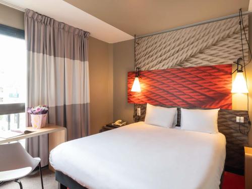 a hotel room with a large bed and a window at ibis Saint Gratien - Enghien-Les-Bains in Saint-Gratien