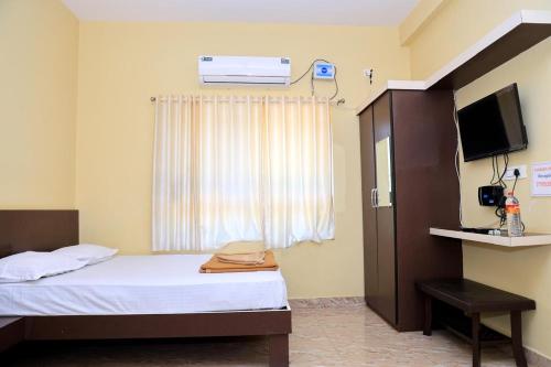 a small room with a bed and a television at Horanadu Sanman residency in Kalasa