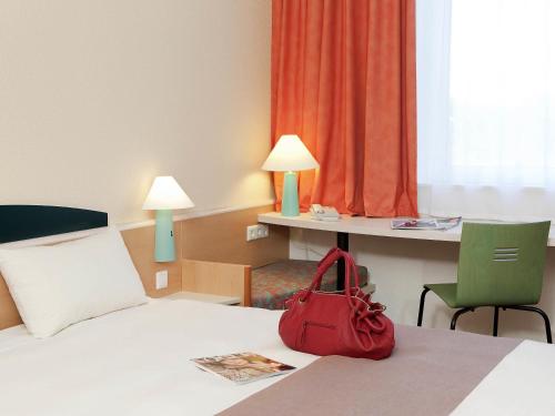 a red purse sitting on a bed in a hotel room at ibis Luxembourg Sud in Livange