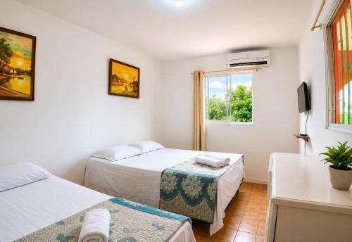 a bedroom with two beds and a window at Suites Mar a Vista in Porto De Galinhas