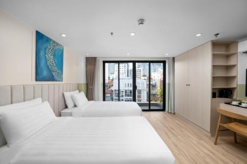 a hotel room with two beds and a desk at Little Charm Boutique Hotel in Hanoi