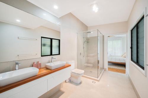 a white bathroom with two sinks and a shower at 15 Derby Road Moffat Beach in Caloundra