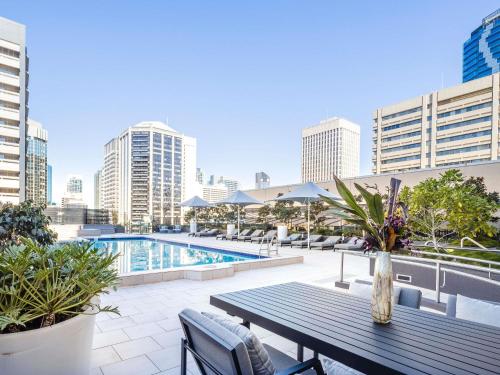 eine Terrasse mit einem Tisch und einem Pool und Gebäuden in der Unterkunft Sofitel Brisbane Central in Brisbane