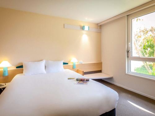 a large white bed in a room with a window at ibis Perpignan Nord Rivesaltes in Rivesaltes