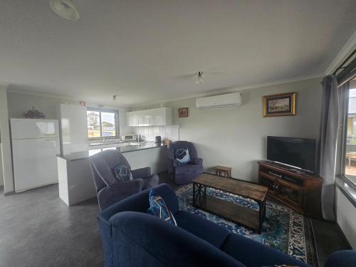 a living room with two blue couches and a kitchen at Wudinna Farm View in Wudinna