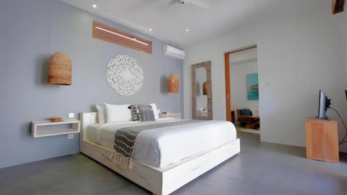 a white bedroom with a bed and a tv at Villa Sarn 1 Sanur in Sanur