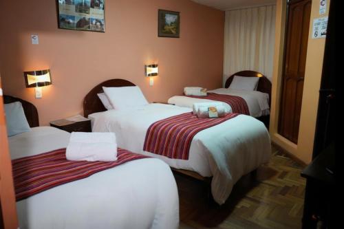 a hotel room with three beds in a room at Hotel Margarita in Puno
