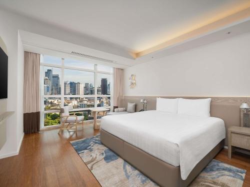 a bedroom with a large bed and a large window at Pullman Bangkok King Power in Bangkok