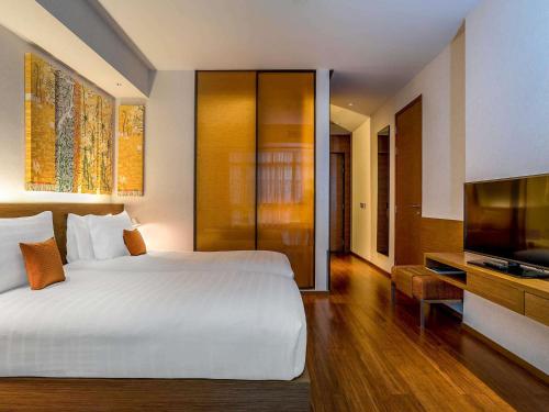 a bedroom with a large bed and a flat screen tv at Pullman Bangkok King Power in Bangkok