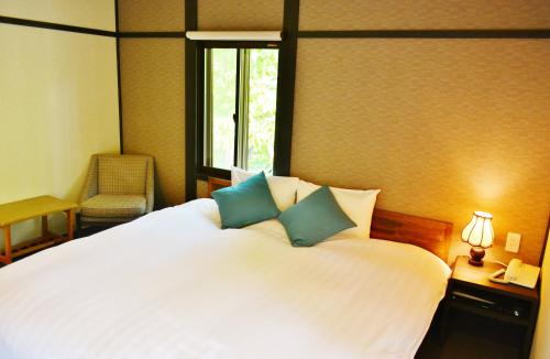 a bedroom with a large white bed with blue pillows at Hakuba Skala Inn in Hakuba