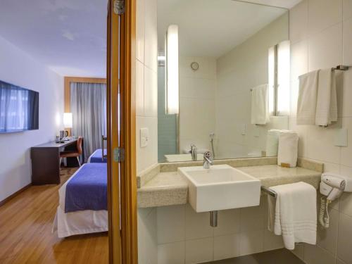 a hotel bathroom with a sink and a bed at Novotel RJ Santos Dumont in Rio de Janeiro