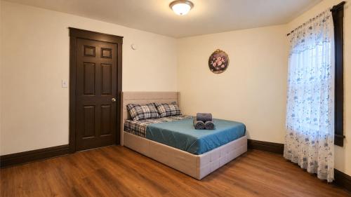 a bedroom with a bed with a blue blanket and a door at Charming 3 Bdr Home 8 mins from the Falls in Niagara Falls