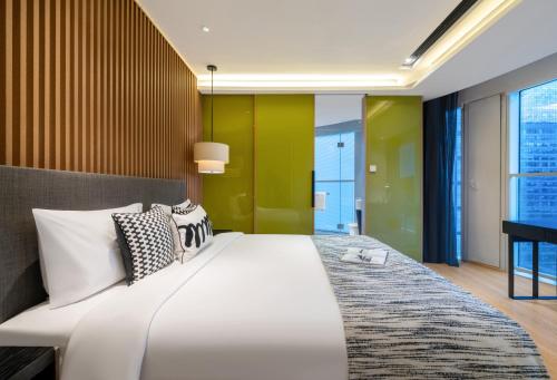 a bedroom with a large bed and a green wall at Citadines South Chengdu in Chengdu