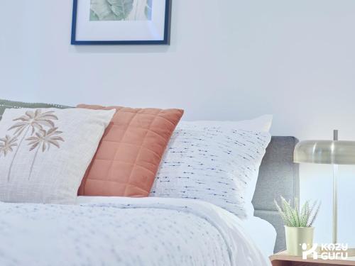 a bed with orange and white pillows on it at KozyGuru | Box Hill | Chic & Close to It All in Box Hill