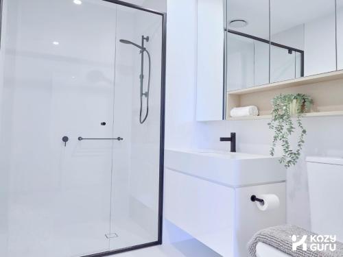 a white bathroom with a shower and a sink at KozyGuru | Box Hill | Chic & Close to It All in Box Hill