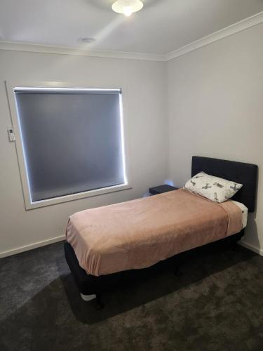 a bedroom with a bed with a large window at 11 Lomond street in Beveridge