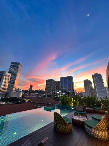 a large swimming pool with chairs and a city skyline at Naumi Hotel Singapore in Singapore