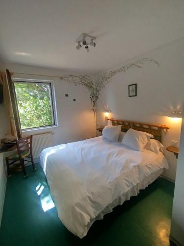 a bedroom with a large white bed and a window at Hôtel Restaurant Le Regimbal in Javols