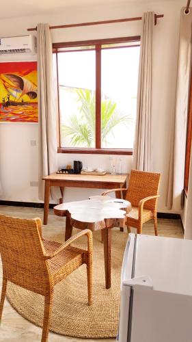 a living room with a table and chairs and a window at Jamaica House in Nungwi