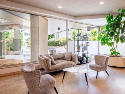 a living room with a couch and chairs and a table at Aparthotel Adagio Paris XV in Paris
