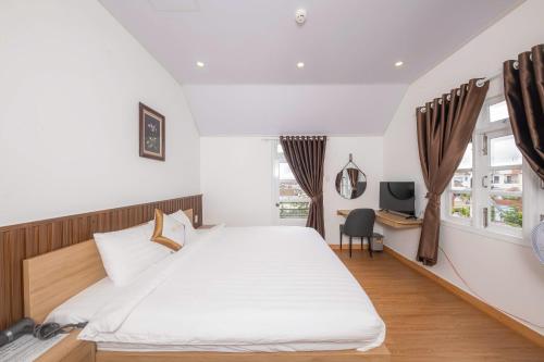 a bedroom with a large white bed and a desk at Minh Đức Villa in Da Lat