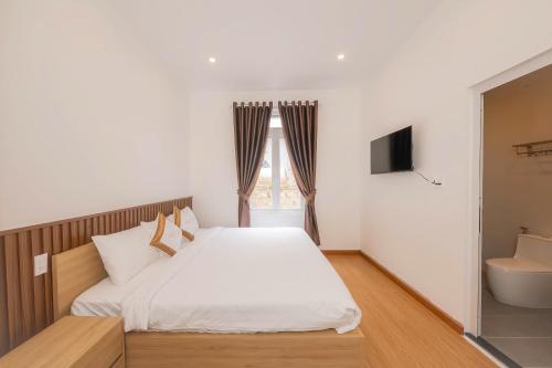 a bedroom with a white bed and a television at Minh Đức Villa in Da Lat