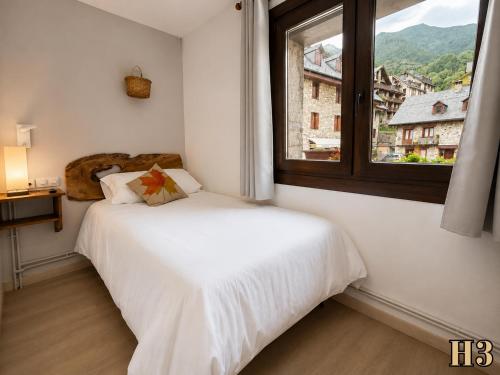 a bedroom with a white bed and a window at Hostal Rural Sant Climent - Habitacions i Apartaments in Taüll
