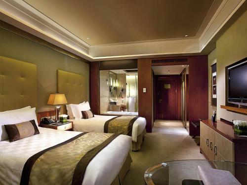 a hotel room with two beds and a television at Sofitel Harbin in Harbin