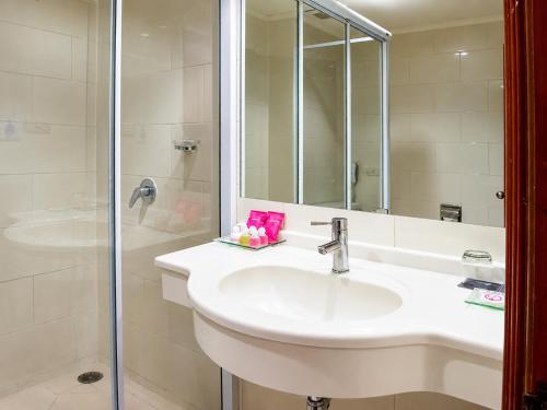 a white bathroom with a sink and a shower at The Palazzo Hotel in Bangkok
