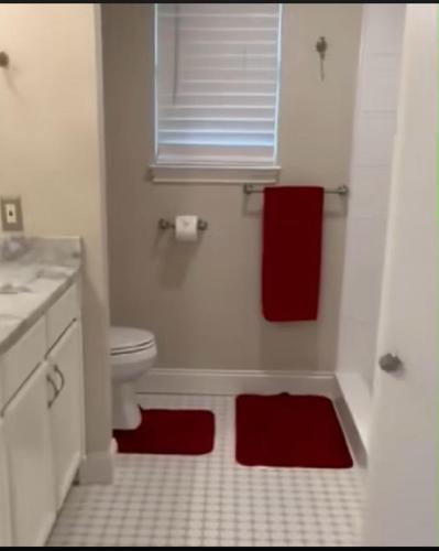 a bathroom with a toilet and two red towels at Abundant Life in Arlington