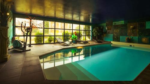 a large swimming pool in a room with a large window at The Originals City, Hôtel Le Village Provençal, Aix-en-Provence Nord (Inter-Hotel) in Pertuis