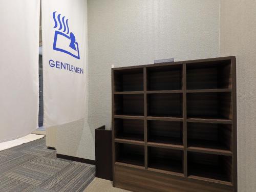 a wooden book shelf sitting next to a wall at Astil Hotel Shinosaka Precious in Osaka