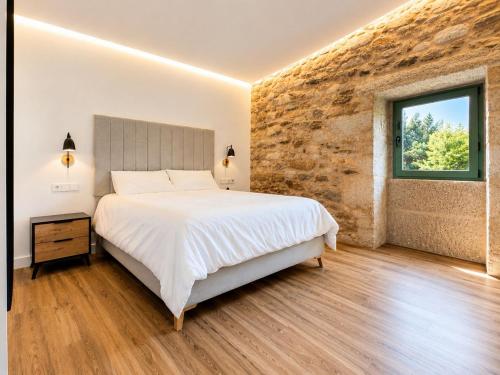 a bedroom with a bed and a brick wall at Casa rural Villa Quintans in Soutullo