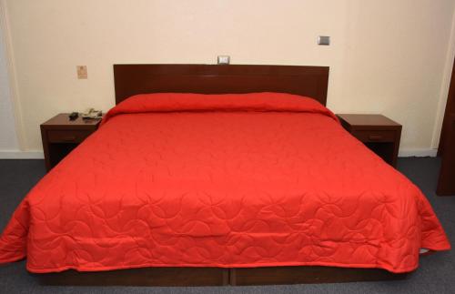 a bed with a red comforter and two night stands at Hotel Maria Victoria Xalapa in Xalapa