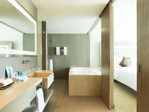 a bathroom with a bed and a bath tub and a sink at Novotel Tangerang in Tangerang