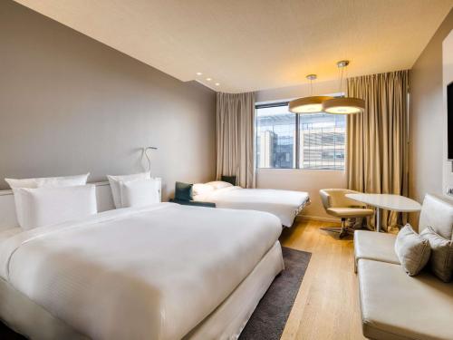 a hotel room with two beds and a couch at Pullman Brussels Centre Midi in Brussels