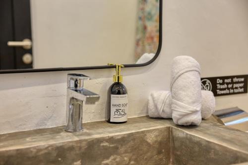 a bathroom sink with a bottle of soap and a mirror at Nalumi Villa in Nusa Penida