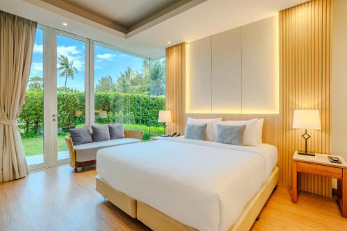 a bedroom with a large white bed and a window at Andaman Pool Villas, Maikhao Beach Phuket in Mai Khao Beach