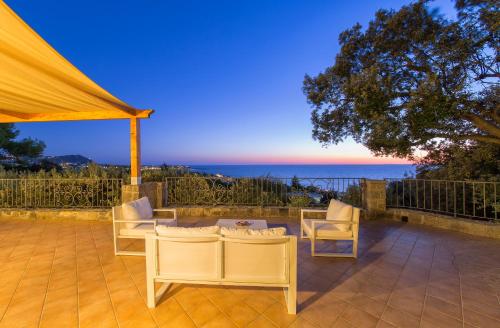 a patio with a table and chairs and the ocean at Villa dei Lecci - 7 Luxury villas with private pool or jacuzzi in Ischia