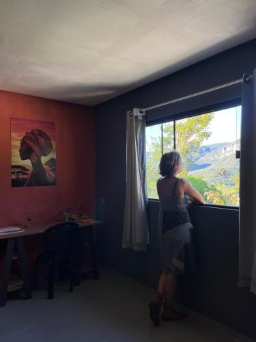 a woman standing in a room looking out a window at Casa Jatobá in Ibicoara