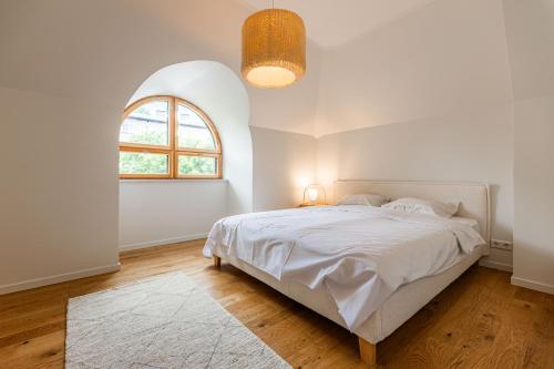 a white bedroom with a bed and an arched window at Komandandi City Center Apartments in Kuressaare