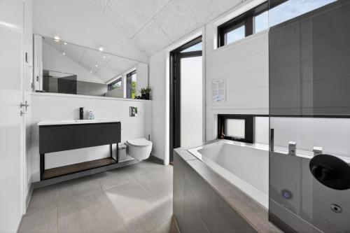 a bathroom with a tub and a toilet and a sink at Luxurious Holiday Home with Sauna & Outdoor Hot Tub in Hejls