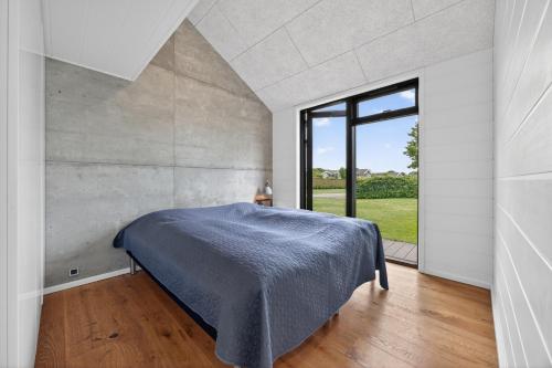 a bedroom with a bed and a large window at Luxurious Holiday Home with Sauna & Outdoor Hot Tub in Hejls