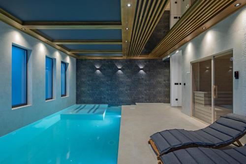a swimming pool with two chairs in a room at Villa Dujma Pool & Spa in Kostrena