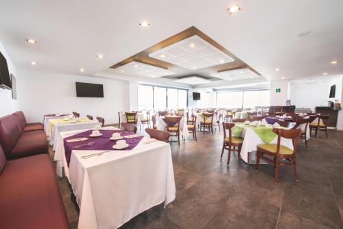 a dining room with white tables and chairs and windows at La Quinta by Wyndham San Jose Chiapa Puebla in San José Chiapa