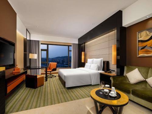 a hotel room with a bed and a television at Pullman Dongguan Changan in Dongguan