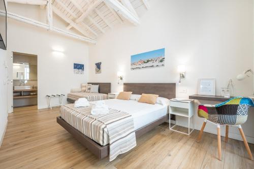 a white bedroom with a bed and a desk at Karú Suites in Cagliari